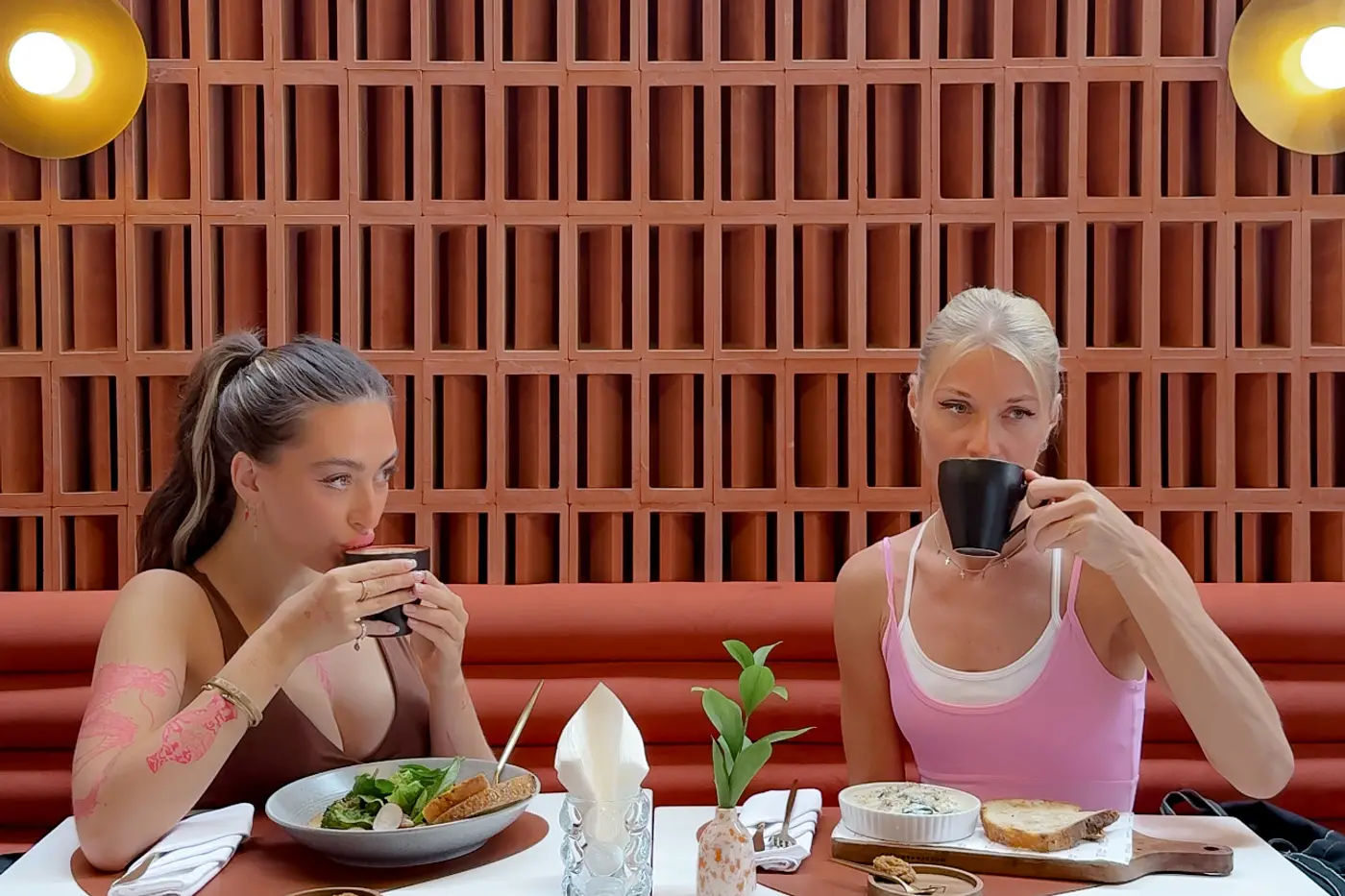 Two guests over coffee and breakfast against the terracotta screen at ASAI Cafe