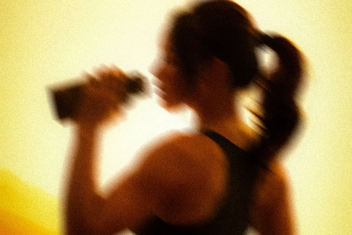 A member drinking from a bottle after a session, backlit in amber